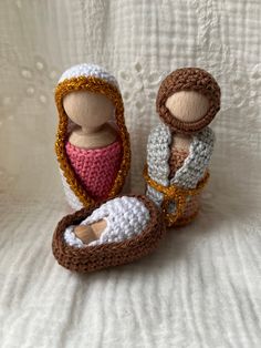 two crocheted dolls sitting next to each other on top of a white blanket