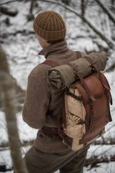 a man wearing a brown hat and jacket with a backpack on his back in the snow