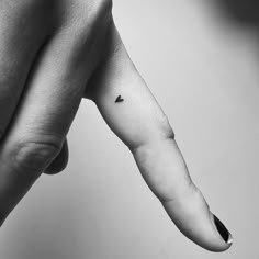 a black and white photo of a person's arm with a tiny triangle tattoo on it