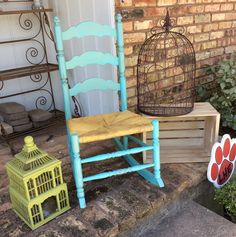 a blue chair sitting next to a yellow birdcage on the steps in front of a brick building