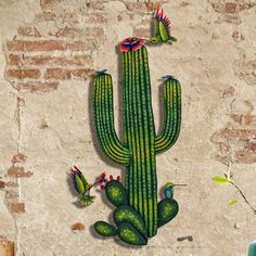 a green cactus with three birds on it next to a brick wall and potted plant