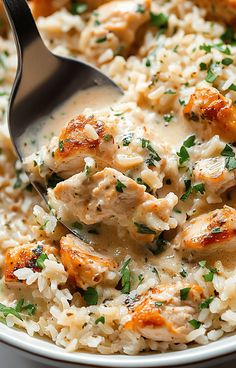 a bowl filled with rice and chicken covered in gravy, garnished with parsley