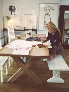 a woman sitting at a wooden table with a laptop computer on top of her desk