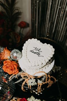 a white cake sitting on top of a table next to orange flowers and other decorations