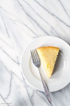 a piece of cake on a white plate with a fork and knife next to it