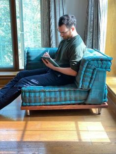 a man is sitting on a couch with his feet up and reading something in front of him