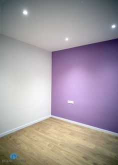 an empty room with purple walls and wooden floors