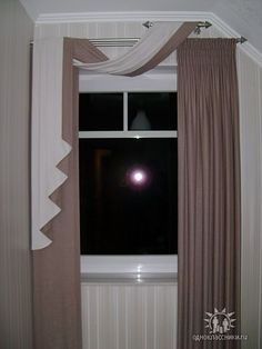 a window with curtains and a light shining in the dark through it's windowsill