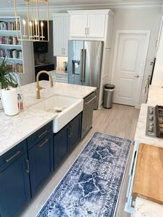 a kitchen with blue and white rugs on the floor next to an open sink