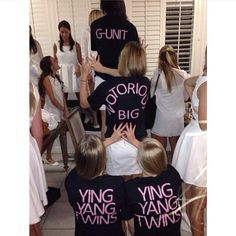 a group of people standing around each other in front of a mirror with pink writing on them