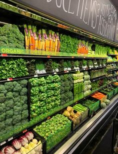 the produce section of a grocery store with vegetables and fruits on display in rows, including broccoli