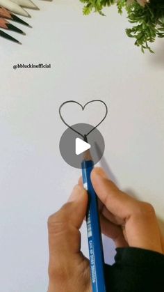 someone is drawing a heart on a piece of paper