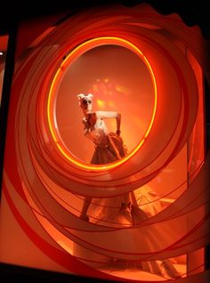 a woman is dancing in front of an orange circle with red and white swirls