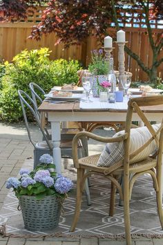 an outdoor dining table with chairs and flowers in the potted planter next to it