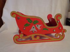 a red and gold sleigh with bells on it sitting on a white sheet