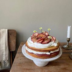 a cake sitting on top of a wooden table next to a white plate with strawberries