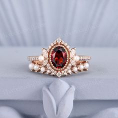 a red and white diamond ring with pearls on the side, sitting on a table