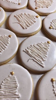 decorated cookies with white icing and gold decorations are arranged on a table in the shape of a christmas tree