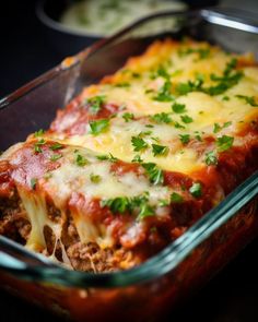 a casserole dish with meat, cheese and parsley in it on a table