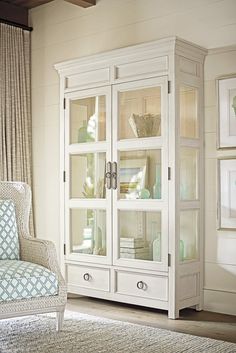 a white cabinet with glass doors in a living room