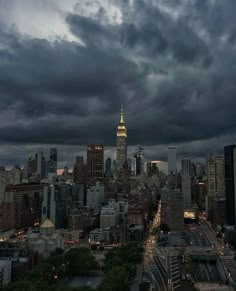 an aerial view of a city at night with dark clouds in the sky and buildings lit up