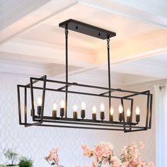 a chandelier hanging from the ceiling in a dining room with flowers and vases