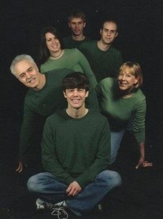 a group of people in green shirts posing for a photo with one man smiling at the camera