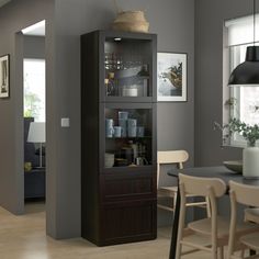 a dining room table with chairs and a tall cabinet in the corner that has wine glasses on it