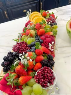 a table topped with fruits and vegetables on top of a white marble countertop next to a bowl of fruit