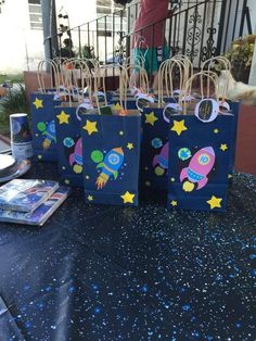 small bags with space themed designs on them sitting on a table in front of a railing