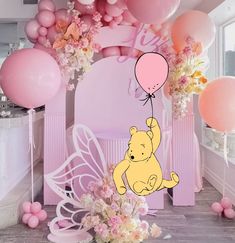 a winnie the pooh birthday party with balloons and flowers