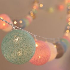 there are several balls hanging from the string with lights in the backgroung