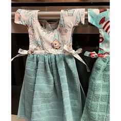 two children's clothing hanging on a rack in front of an oven with pots and pans