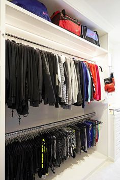 an organized closet with clothes hanging on the wall and other items sitting on shelves in front of it