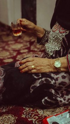 an old woman is holding a glass of wine while sitting on the floor with her dog