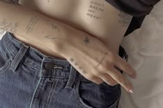 a woman with tattoos on her arm and chest is holding onto the jeans of her stomach