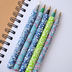 four pens lined up next to each other on top of a notepad and notebook