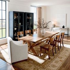 a dining room table surrounded by chairs in front of large windows