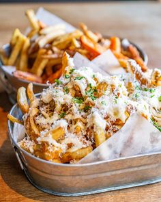 two tins filled with french fries covered in grated cheese and parmesan