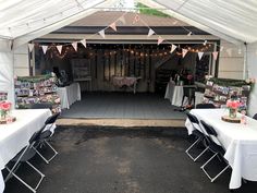 tables and chairs are set up in front of a white tent with pink flowers on it