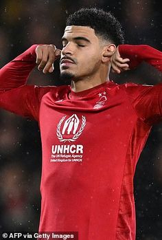 a soccer player is holding his head in the rain