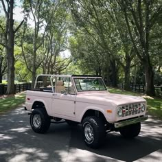 an old pink truck parked in front of some trees