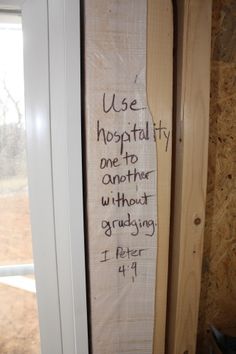 a piece of wood with writing written on it in front of a door and window