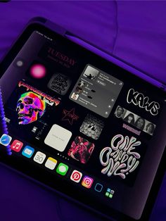 an ipad with various stickers on it sitting in front of a purple background,