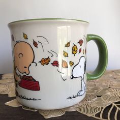 a coffee cup with a snoopy cartoon on the side and leaves falling from it