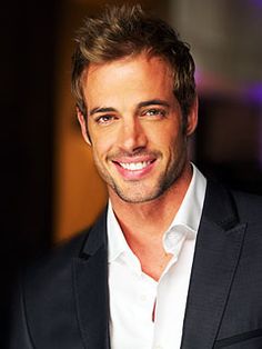 a man in a suit smiling at the camera with his hand on his hip and wearing a white shirt