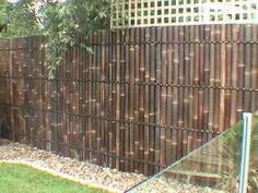 a fence made out of bamboo sticks in the grass next to a tree and bushes