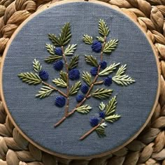 a close up of a embroidery on a piece of cloth with blue flowers and leaves