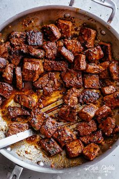 the meat is being cooked in a skillet with tongs and seasoning sugar