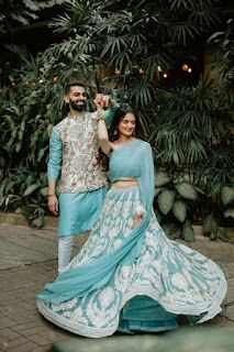 a man and woman standing next to each other in front of some trees with lights